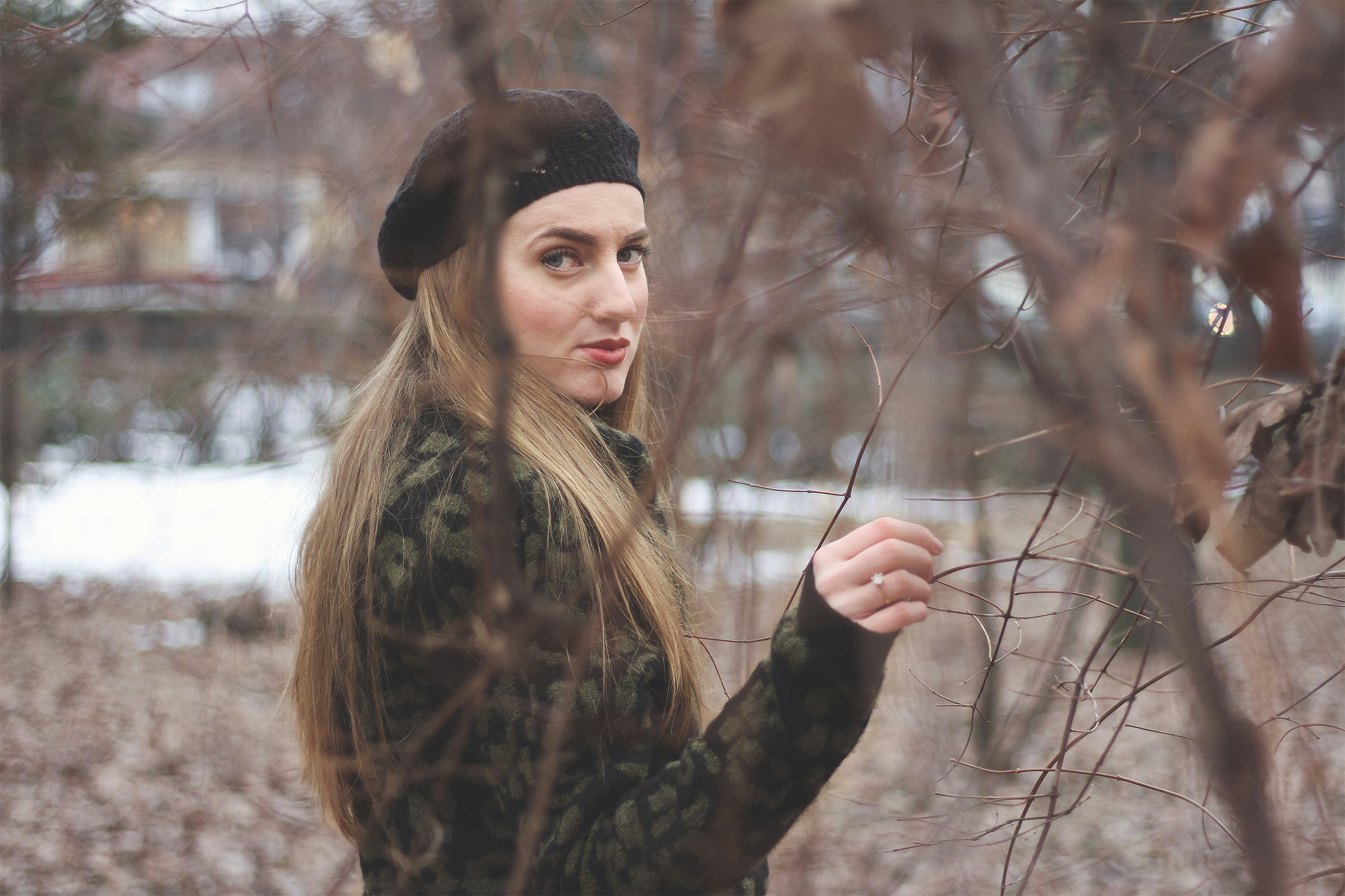 woman in black and brown floral long sleeve shirt and black knit cap standing on brown